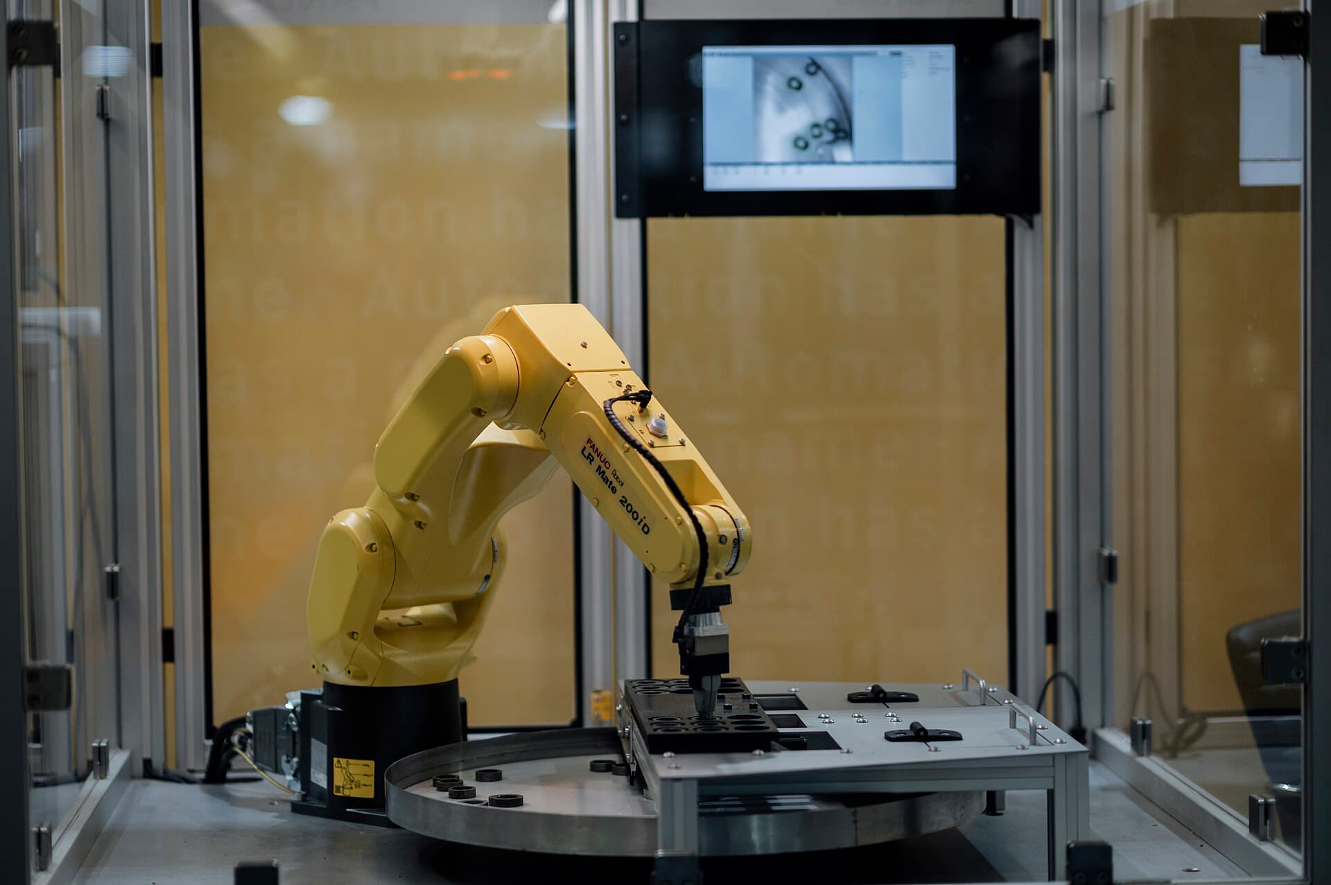 An industrial robot arm placing a component inside a glass lab cell