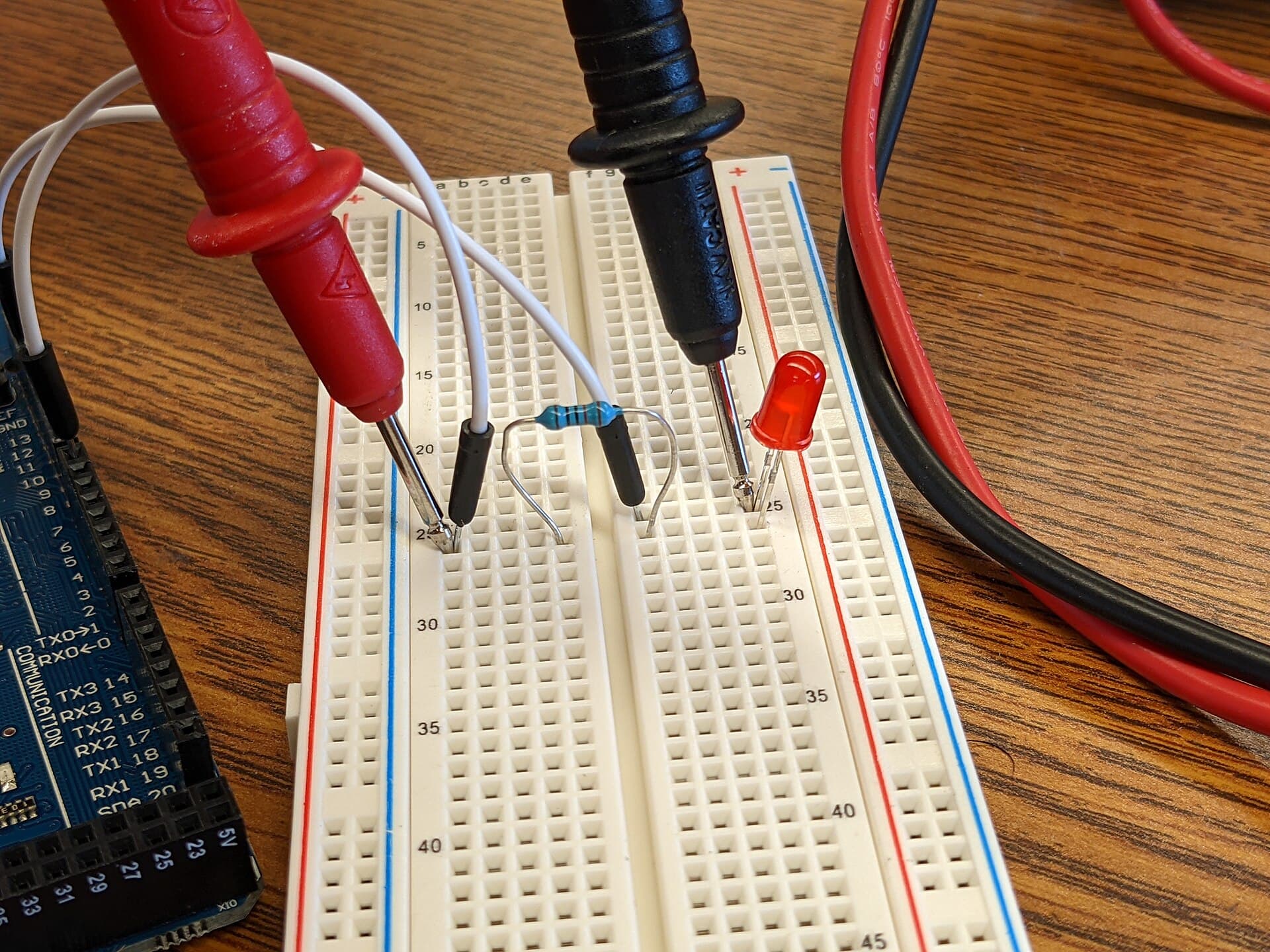 Multimeter probes testing an LED circuit on a breadboard